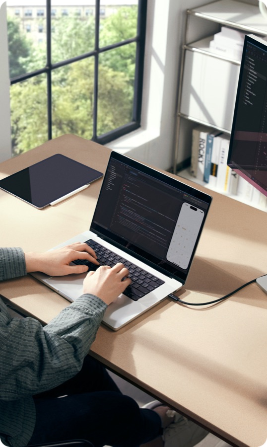 桌上一台 MacBook Pro 正在写代码，旁边放着 iPad 与外接显示器
